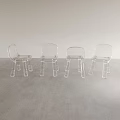 Four Clear Acrylic Leisure Chairs Placed On Gray Floor Against Light Colored Wall