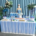 Delicious Food Buffet Table With Fresh Flowers Blue Curtains Fringed Tablecloth And Various Snacks