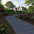 Charming Residential Garden Landscape With Winding Stone Path And Vibrant Blooming Flowers Around Cozy Home