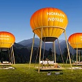 Nomadic Voyage Campsite With Orange Balloon Structures On Grassland Near Mountains
