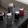 Modern Kitchen Appliances Featuring Colorful Kettles Placed on Black Table Top