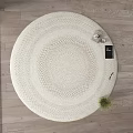 Round White Woven Rug on Wooden Floor with Decorative Items and Small Plant