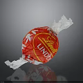 Lindt Lindo Red Candy With White Leaf Pattern On Crinkled Wrapper Against Black Background