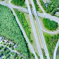 Aerial View Of Highway Bridge With Green Trees Road Intersections Residential Areas And Curved Ramps