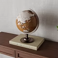Decorative Globe on Wooden Tabletop With Beige Base and Small Green Plant