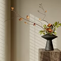 Black Vase with Orange Blooms Green Leaves and Branches on Wooden Pedestal with Sunlight Shadows