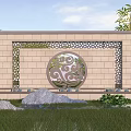 Stone Landscape Wall With Ornate Circular Carving And Surrounding Green Plants Rocks And Lawn