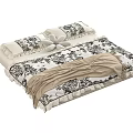 Cozy Bed with Black and White Floral Bedding Pillows and Beige Blanket