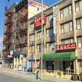 Vibrant Urban Commercial Street With Chinese Signs Red Fire Escapes And Green Awnings