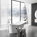 White Bathtub with Large Windows Overlooking Snowy Mountains Trees and Side Cart Holding Towels