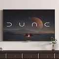 Wall Mounted TV Displaying Dune Desert Landscape With Planet On Wooden Cabinet With Decorative Items