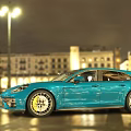 Turquoise Sports Car On Night City Street With Headlights Shiny Wet Road And Modern Buildings