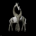 Two White and Gray Giraffe Sculptures With Intertwined Necks and Decorative Blanket