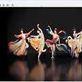 Women dancing in colorful traditional costumes with flowing skirts against black background on reflective floor