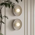 Round Striped Wall Lamps Mounted On Light Colored Paneled Wall With Green Plant Leaves