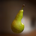 Fresh Green Pear With Bite Mark And Exposed Juicy Flesh On Blurred Background