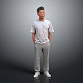 Man Standing Hands in Pockets Wearing White T-Shirt Gray Sweatpants White Sneakers on Gray Background