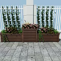 Decorative Garden Planters With Tall Green Plants Pink Flowers Against White Fence Stone Pavement