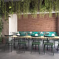 Warehouse Restaurant Dining Area With Green Plant Wall Brick Wall Wooden Tables And Green Chairs