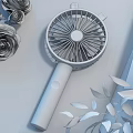 Portable Handheld Fan With Pink Blades And White Handle Near Green Leaves And Flowers
