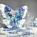 Butterfly Shaped Floral Installation With Blue And White Flowers Balloons Candles And Scattered Petals