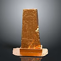 Golden Obelisk Sculpture with Intricate Carved Patterns on Stable Base
