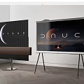 Two Modern Televisions On Stands With Soundbar And Scenic Screens In Wooden Room