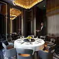 Elegant Private Dining Room With Round Table White Tablecloth Gray Chairs And Yellow Centerpiece