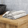 Black Stone Sink with Silver Faucet on Wooden Countertop and Stone Containers Against Gray Wall