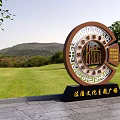 Circular Legal Culture Themed Sculpture With Traditional Patterns In Square Green Grass Trees And Mountains
