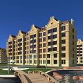 Multistory Residential Building With Yellow Exterior Red Roof Green Lawn Pond Wooden Bridge And Decorative Stones