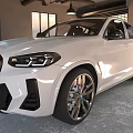 White Sleek Sporty SUV Parked In Interior Garage With Roller Doors And Black Alloy Wheels