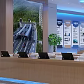 Modern Lobby Interior With Wooden Reception Desks Seating Large Screen Blue Lighting And Plants