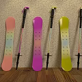 Pink Purple Yellow Snowboards And Ski Poles Leaning Against Wall On Wooden Floor
