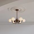 Brass Chandelier With White Spherical Lampshades On White Ceiling With Circular Plaster Moldings And Trim