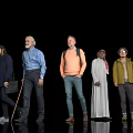 Diverse Group Of People With Different Ages And Outfits Standing Against Black Background