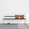 Black Bench with Two Orange Cushions and Black Shoes Against White Wall and Gray Floor