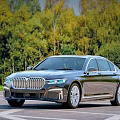 Black BMW 7 Series Luxury Sedan Parked Against Green Tree Background