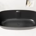 Black Bathtub With Black Faucet And Wall Niche Holding Oil Bottle And Candles