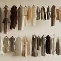 Various Styles Different Colors Clothes Hanging On Hangers Against Light Colored Wall
