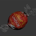 Lindt Lindo Red Candy With White Leaf Pattern On Crinkled Wrapper Against Black Background