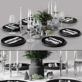 Modern Tableware Set with Black Plates Stainless Steel Cutlery Wine Glasses Candles and Green Foliage