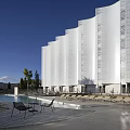 Modern White Building With Wavy Facade Windows Front Grass Swimming Pool And Lounge Chairs