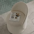Beige Plush Single Sofa with Open Magazine Featuring Shells on Green Geometric Patterned Floor