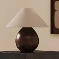 Teardrop Shaped Wooden Table Lamp with Beige Linen Shade on Black Stand and Wall Art