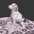 White and black spotted dog sitting on gear-patterned cloth looking up with gray background