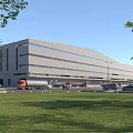 Modern Industrial Factory Building with Large Windows Trucks in Front Parking Area and Green Lawn