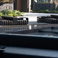 Black Outdoor Sofa Set In Modern Patio With Lush Greenery And Water Feature