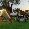 Garden Landscape with Treehouse Illuminated Slide Lawn People Gathering Canopies and Lanterns at Sunset