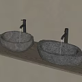 Stone Oval Washbasins On Wooden Countertop With Black Faucets And Light Colored Wall